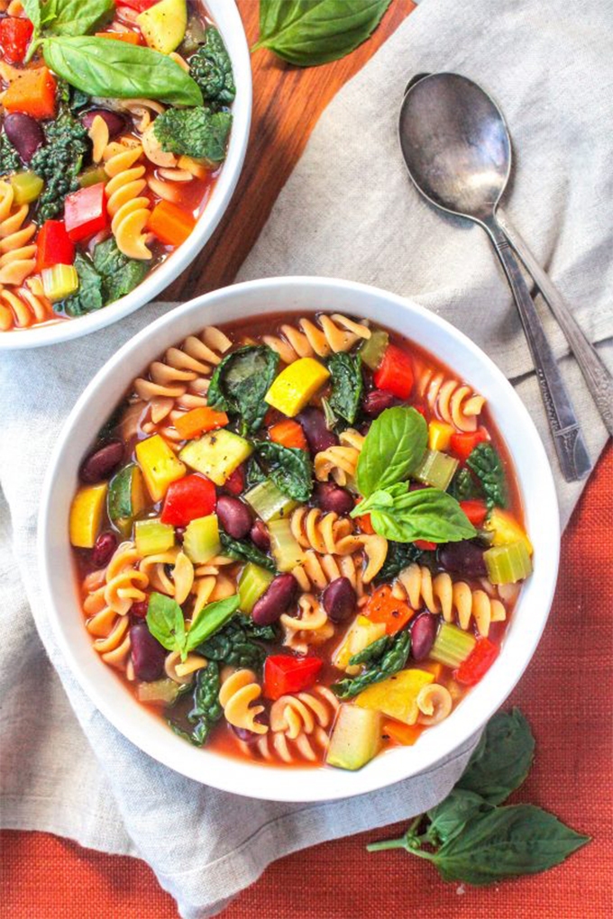 A bowl of vegan minestrone topped with sprigs of basil