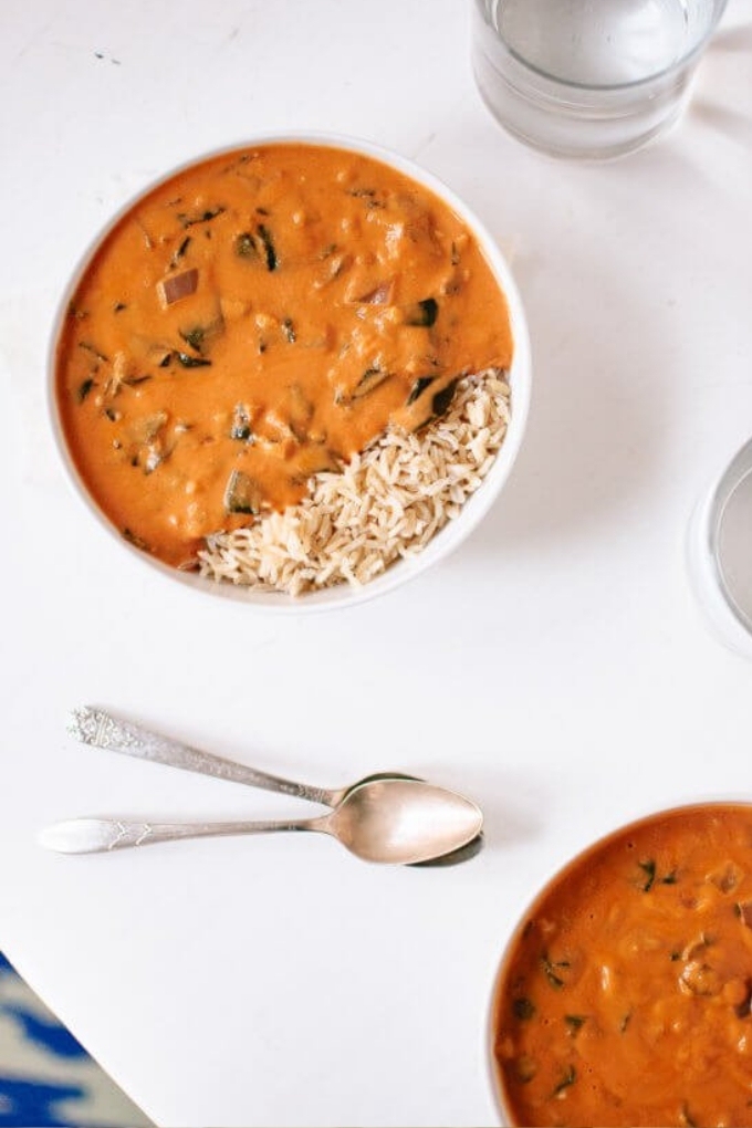An overhead shot featuring two bowls of West African Peanut Soup served alongside brown rice