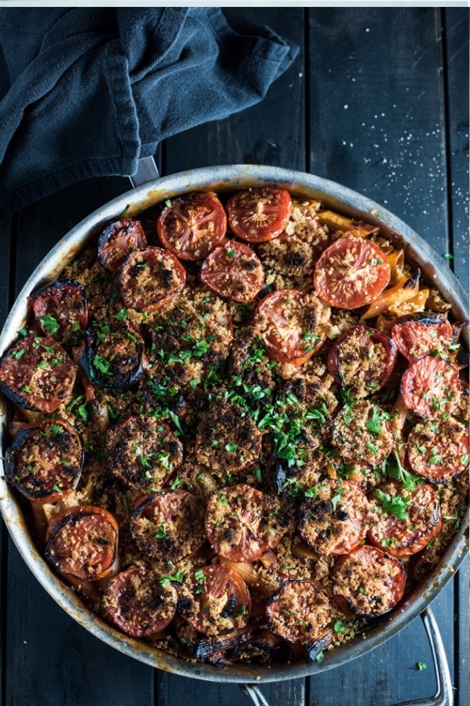 A skillet serving vegan pasta topped with sundried tomatoes and basil