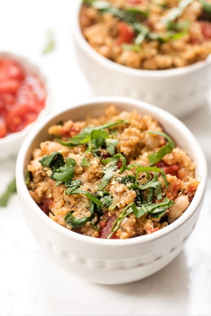A white bowl filled with Italian quinoa salad topped with ribbons of basil