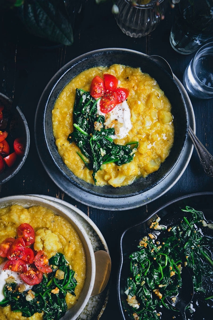 Two bowls of vegan dal topped with sauteed spinach and tomatoes