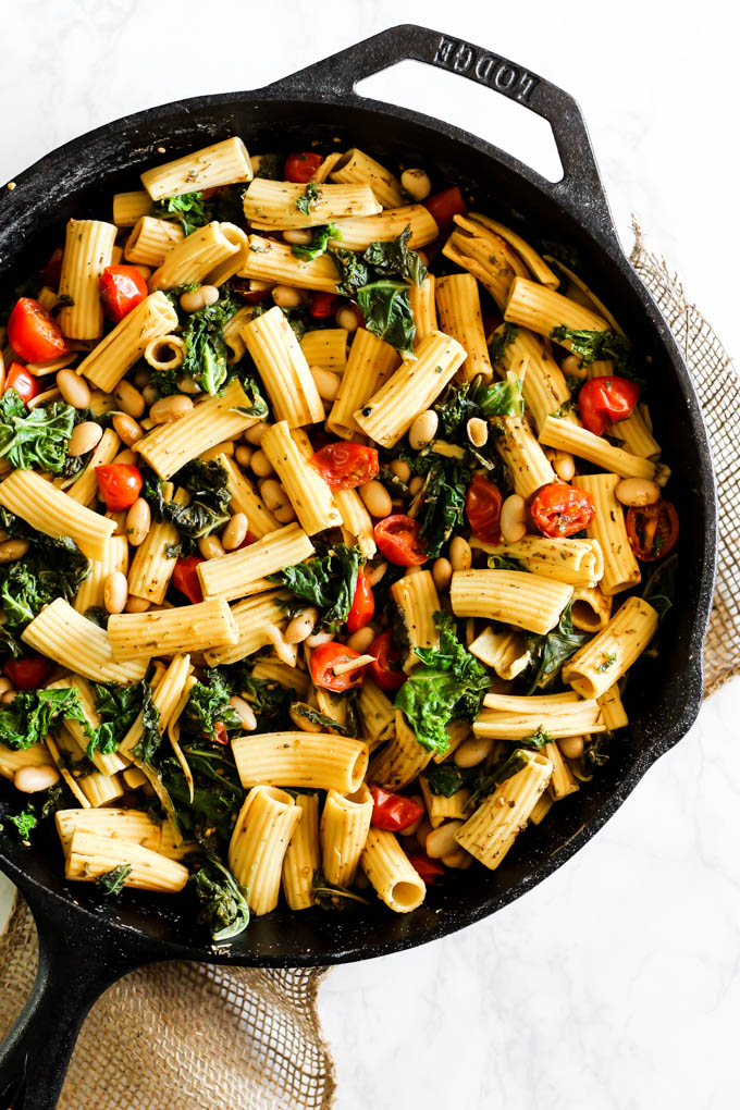 An overhead shot of a cast iron skillet serving a tomato kale pasta dish