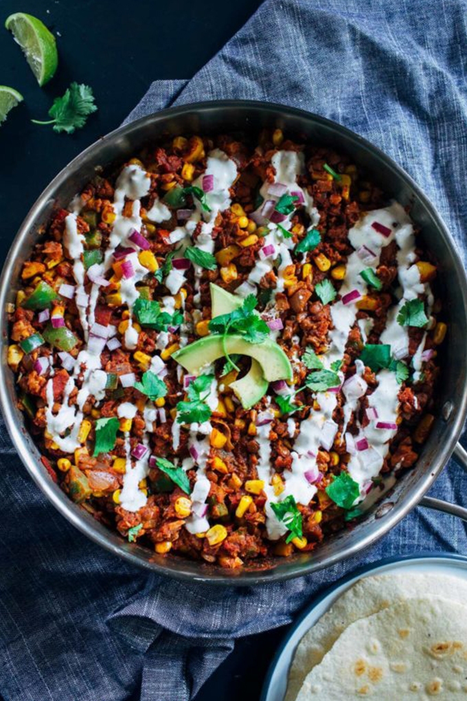 A vegan taco skillet topped with vegan sour cream and sliced avocado