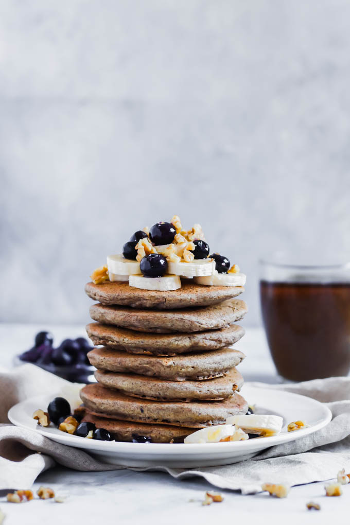 A plate of vegan buckwheat pancakes served with a cup of coffee