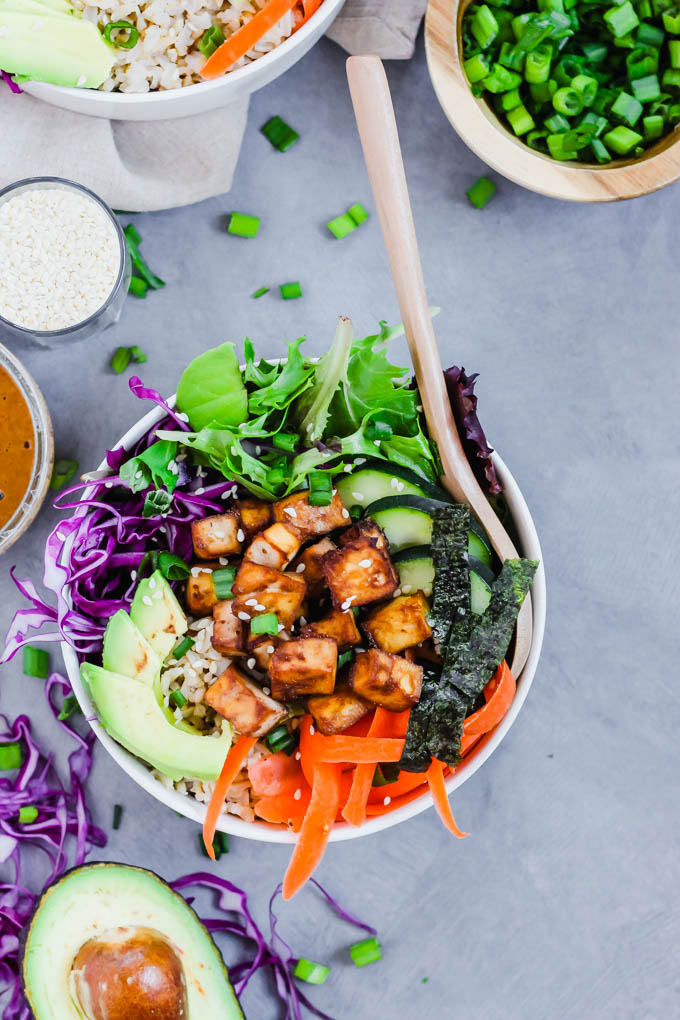 a vegan poke bowl served next to sides of vegan sauces