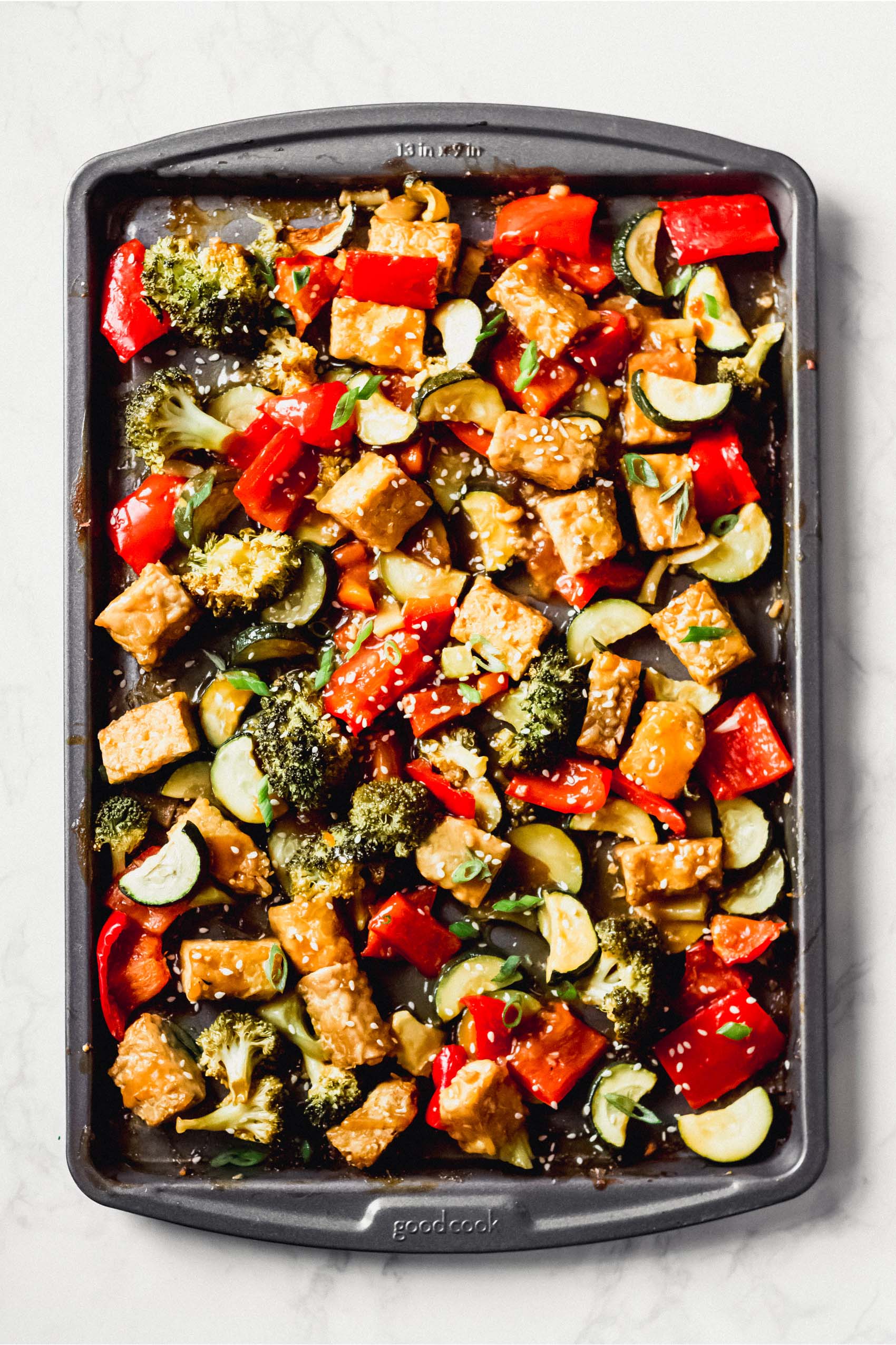 a sheet tray full of chopped vegetables and cubed tempeh