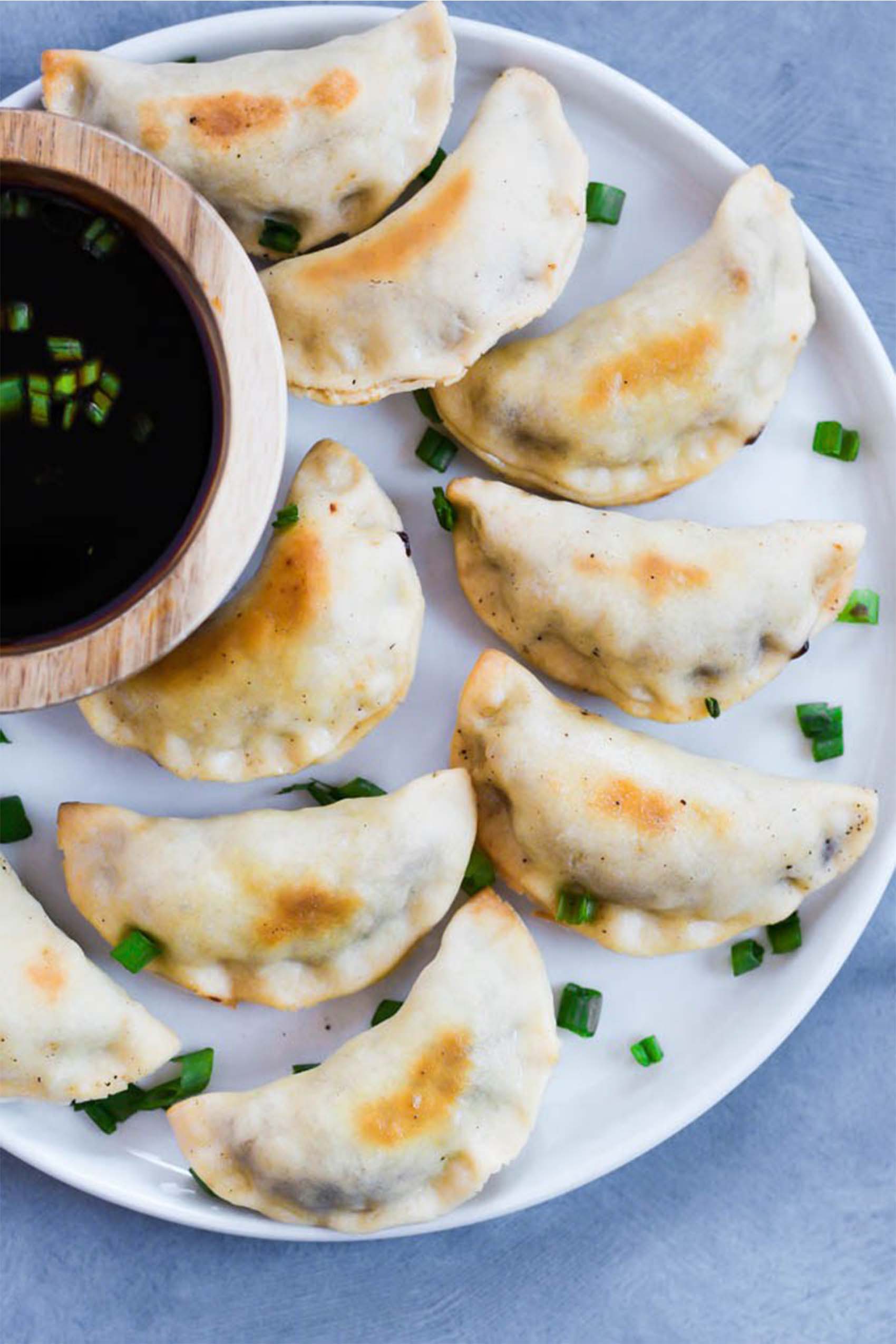 a plate of vegan pot stickers served with a side of soy sauce