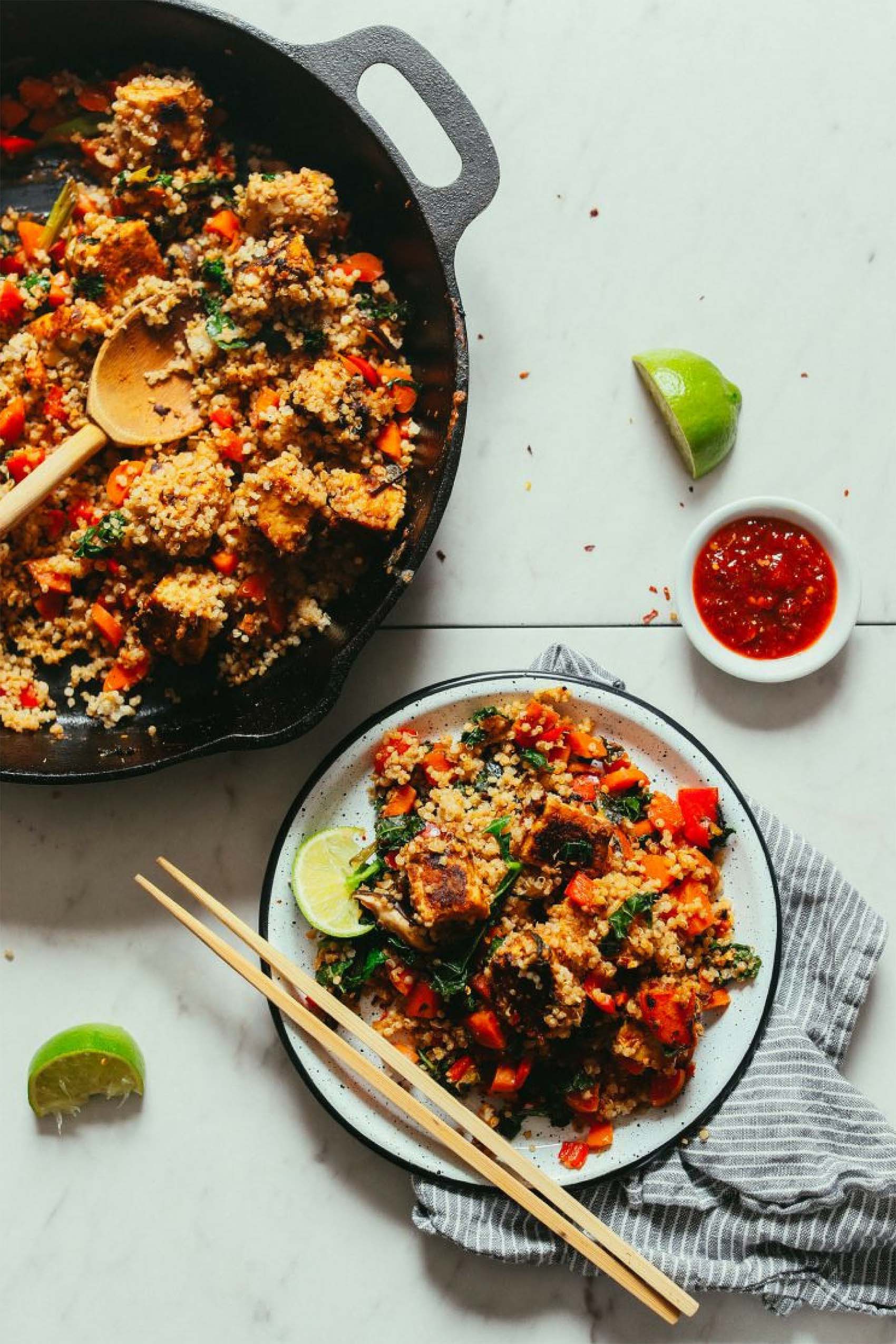 a skillet of vegan stir fry next to a single serving on a plate