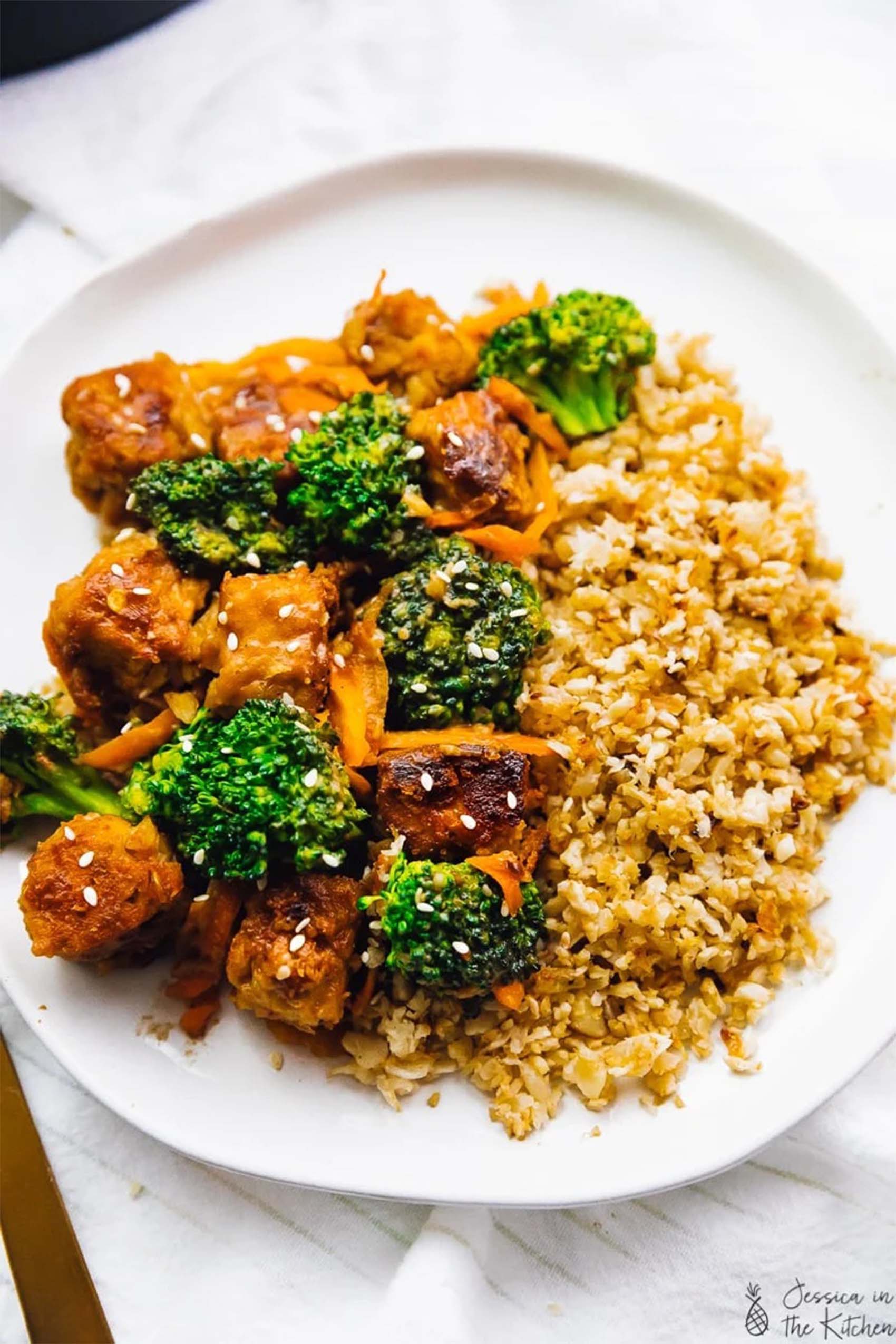 a plate of rice and fried tempeh served with broccoli