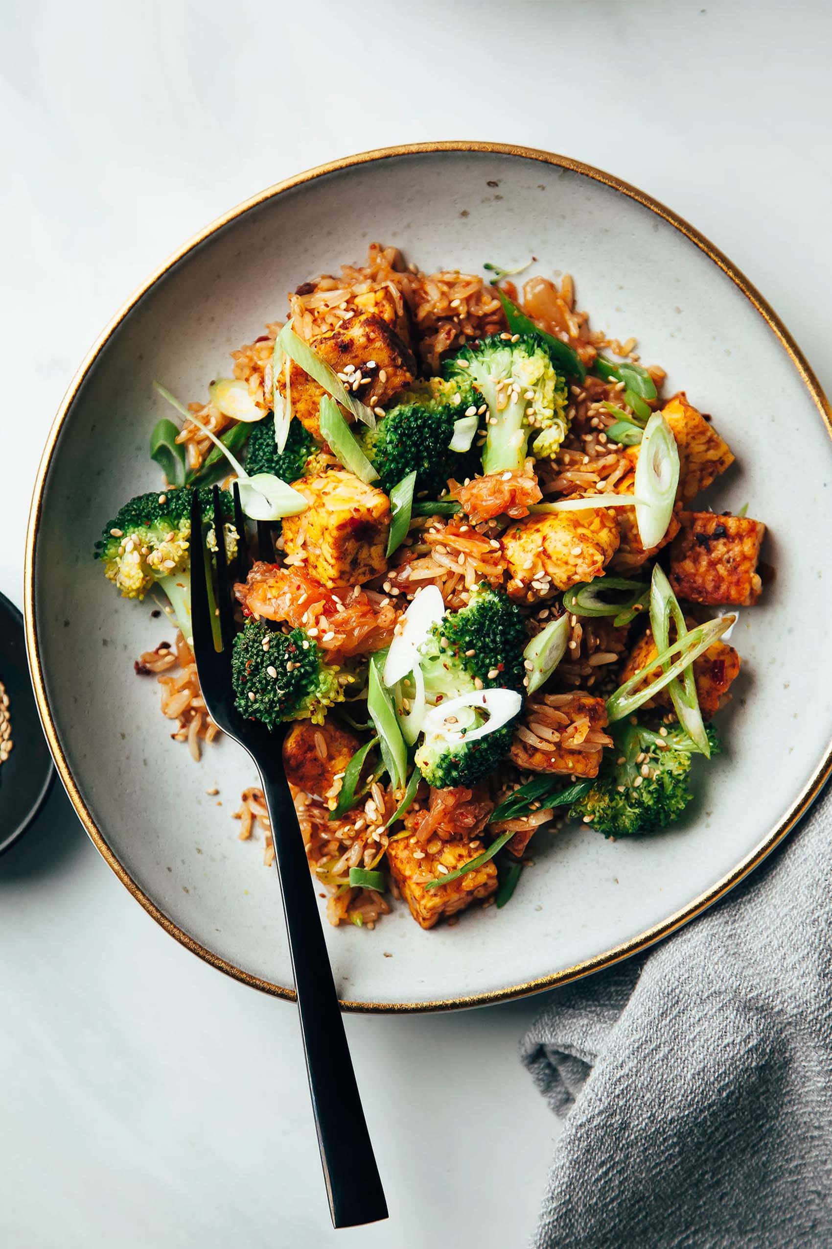 a plate of vegan tempeh stir fry topped with sliced green onions