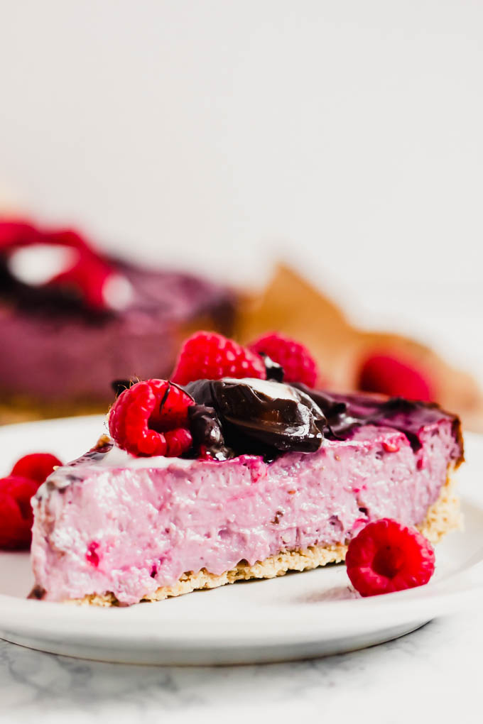 a piece of dairy free raspberry cheesecake topped with chocolate sauce and raspberries