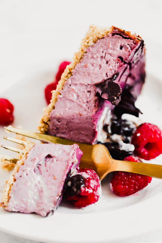 a fork slicing into a piece of vegan raspberry cheesecake