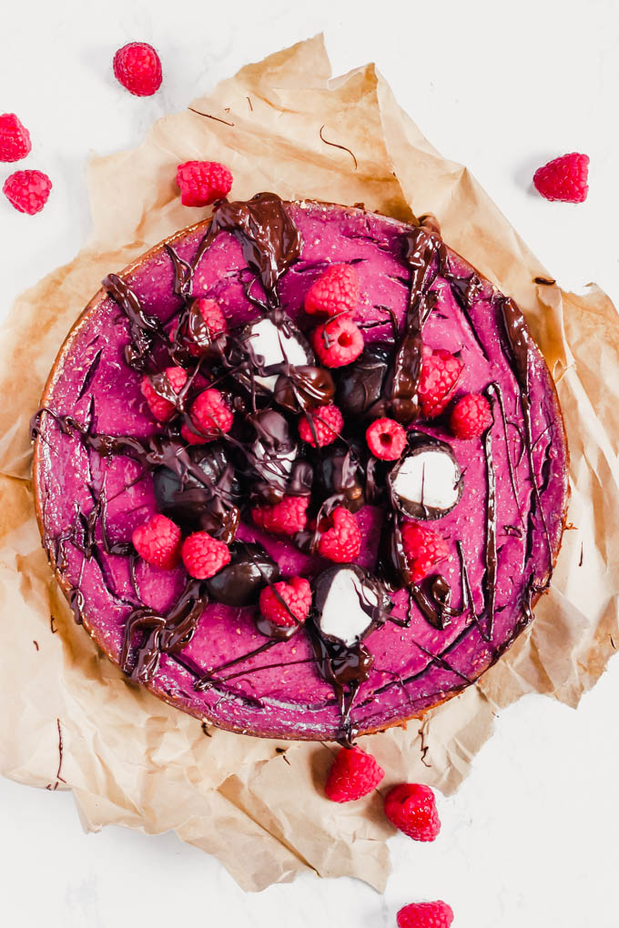 a vegan raspberry cheesecake topped with fresh berries and chocolate