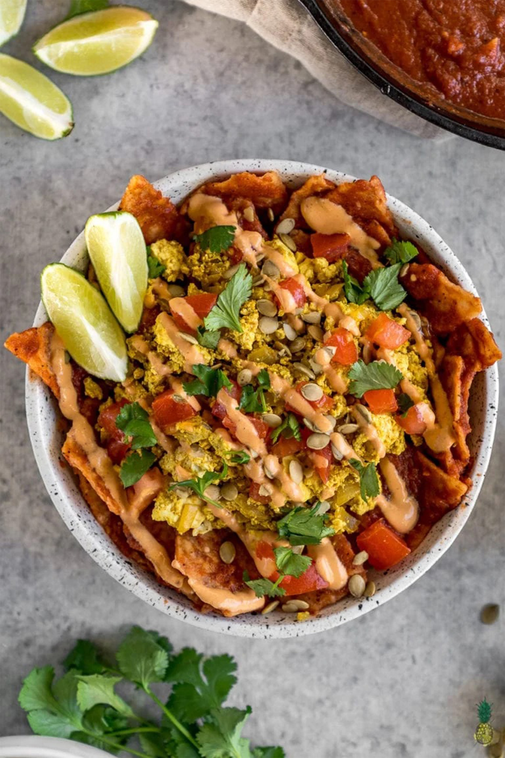 a bowl of vegan chilaquiles rojas served with two wedges of lime