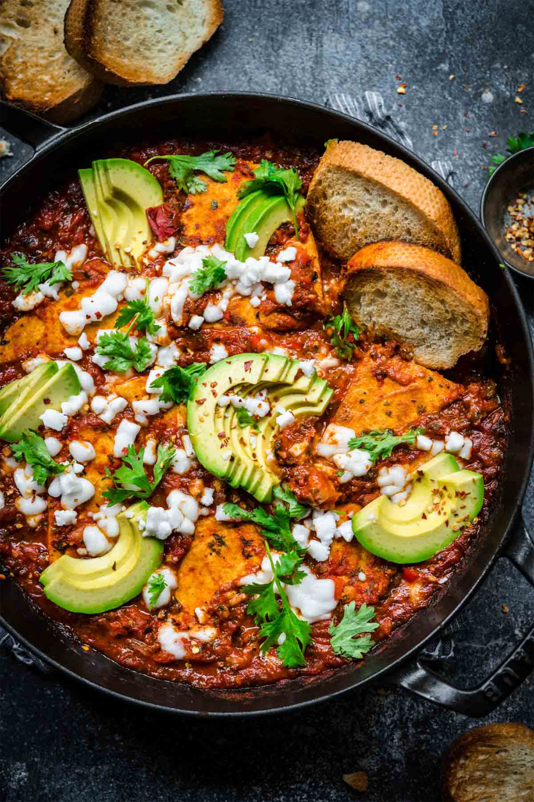 a cast iron skillet of vegan shakshuka served with toasted bread