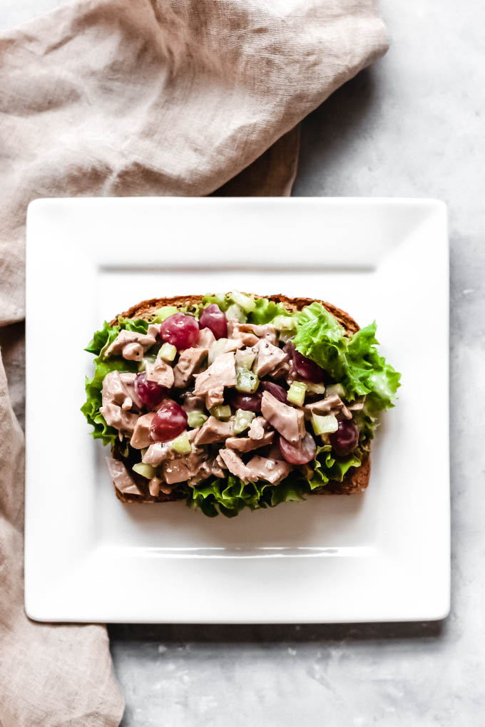 a half of a sandwich with vegan chicken salad spread on top of a leaf of lettuce