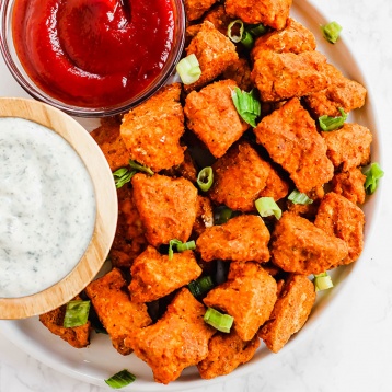 a plate of vegan chicken nuggets served alongside ranch and ketchup
