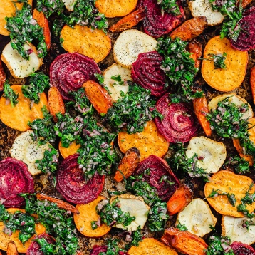 a tray of roasted vegetables topped with chimichurri