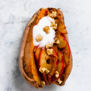 A baked sweet potato fulled with stewed apples, walnuts and vegan yogurt