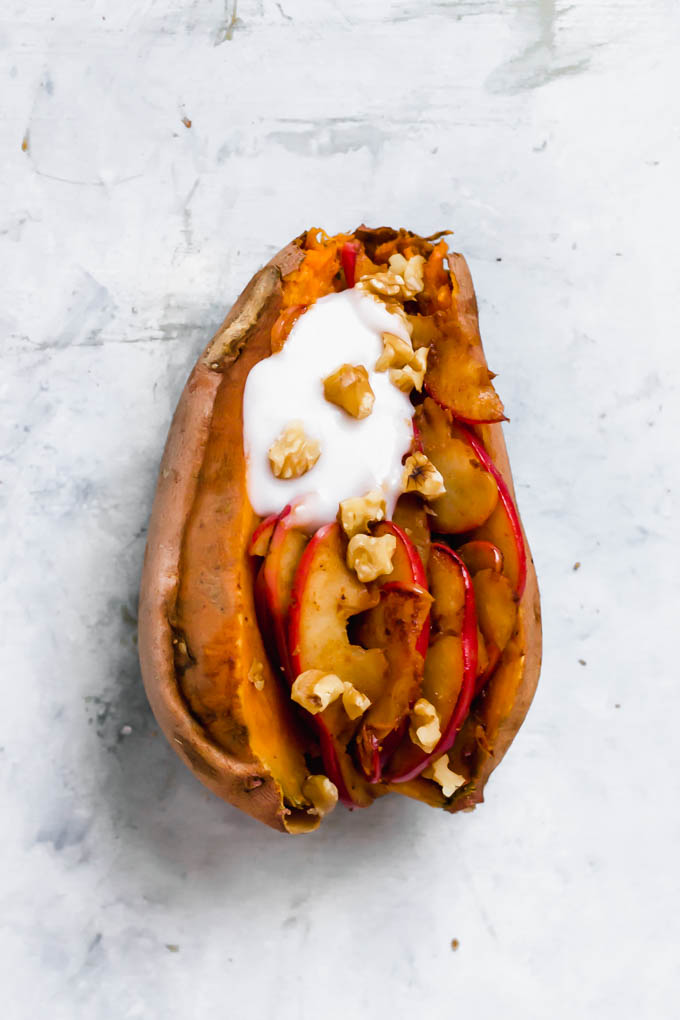 A baked sweet potato fulled with stewed apples, walnuts and vegan yogurt