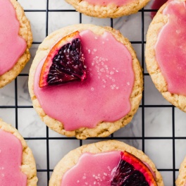 a vegan sugar cookie with blood orange glaze topped with an orange segment and a sprinkle of sugar