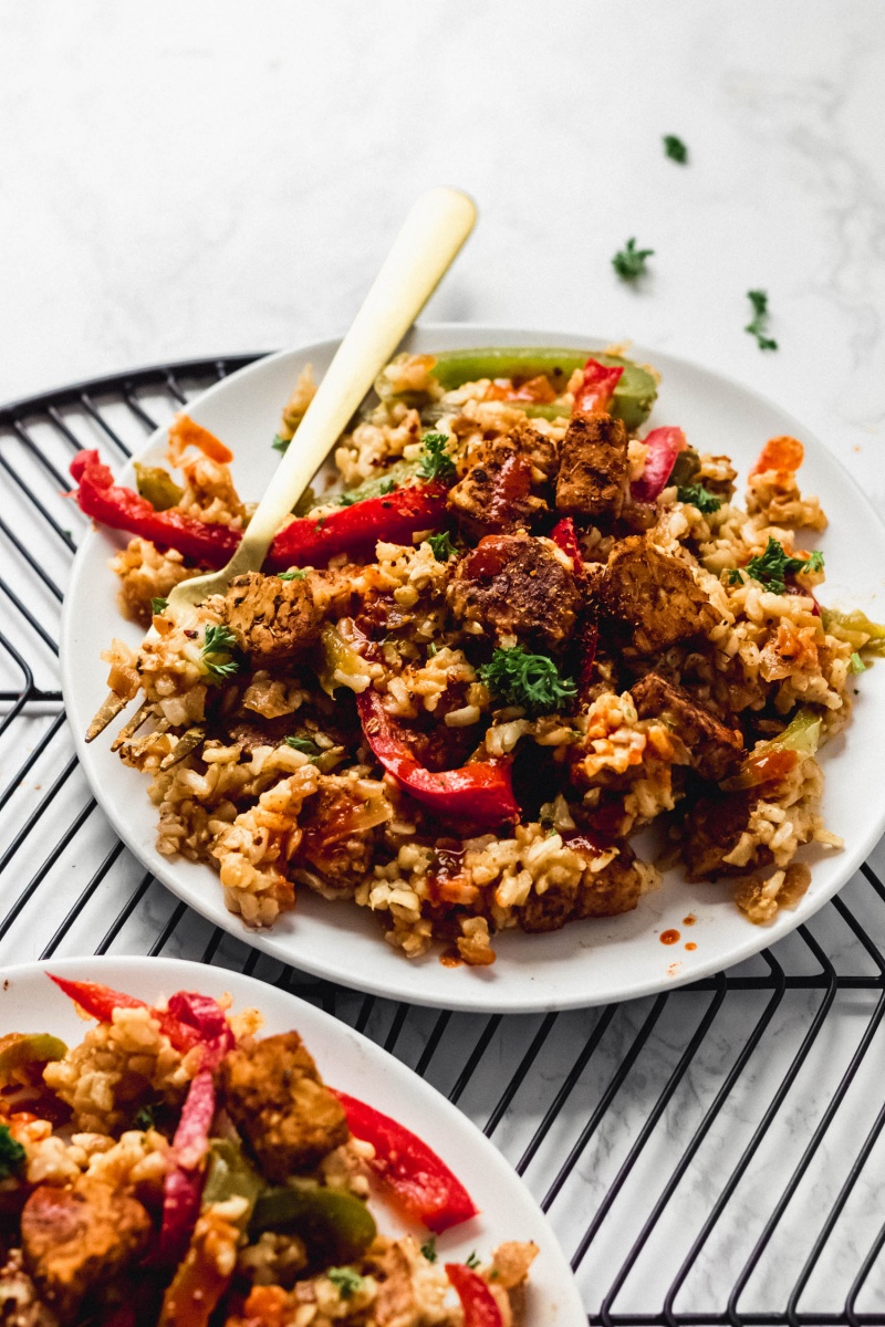 A plate of fried tempeh and cajun rice topped with fresh parsley