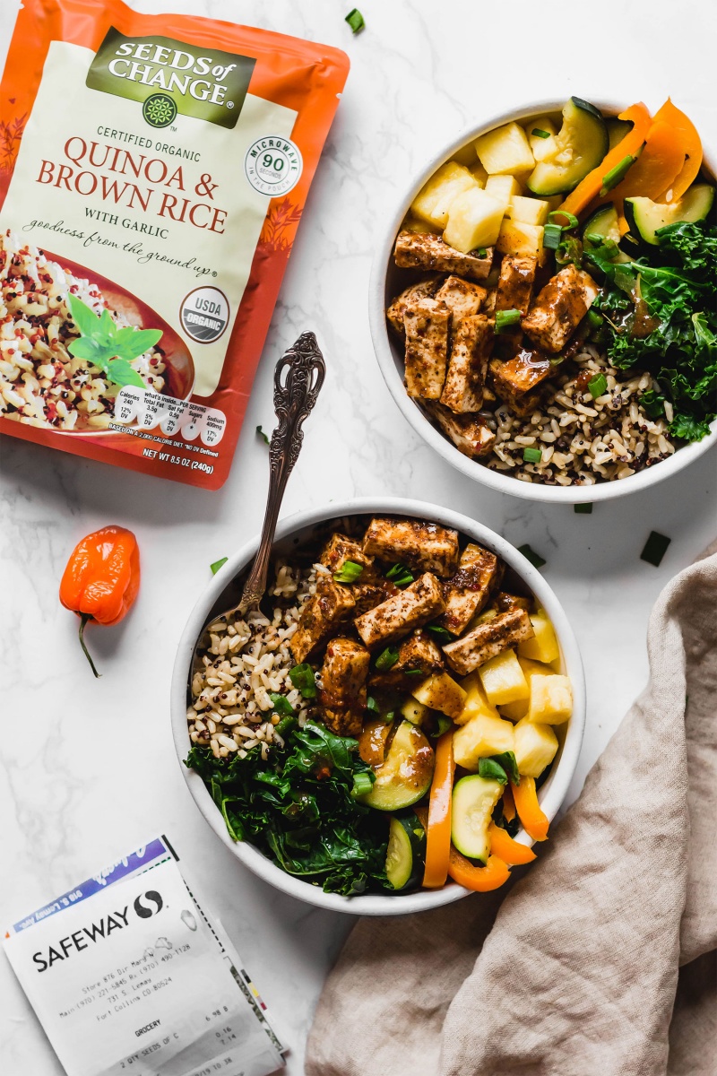 two jerk tofu power bowls next to a bag of microwaveable brown rice