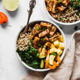 a jerk tofu power bowl with veggies, rice, tofu and pineapple