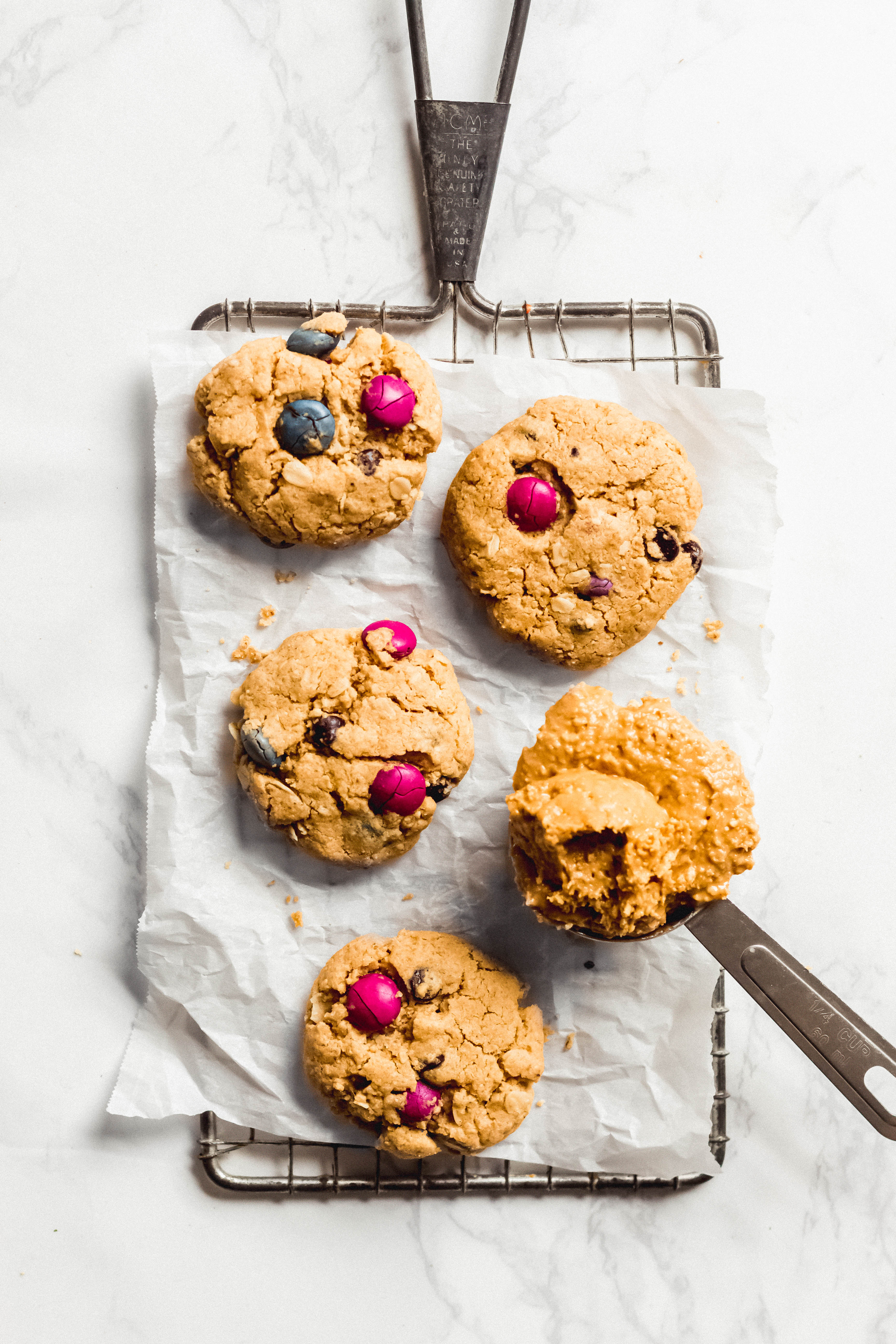 a tablespoon of peanut butter next to a batch of four monster cookies