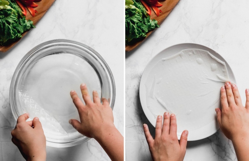 hands placing rice paper wraps in a bowl of water