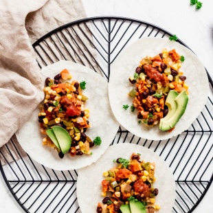 three sweet potato and black bean tacos topped with sliced avocado