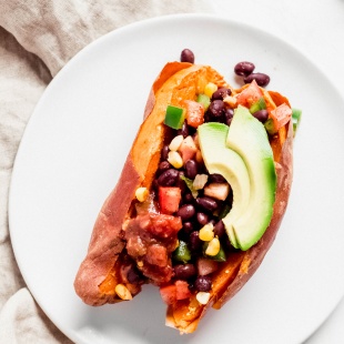 a stuffed sweet potato filled with black beans, corn and diced tomatoes