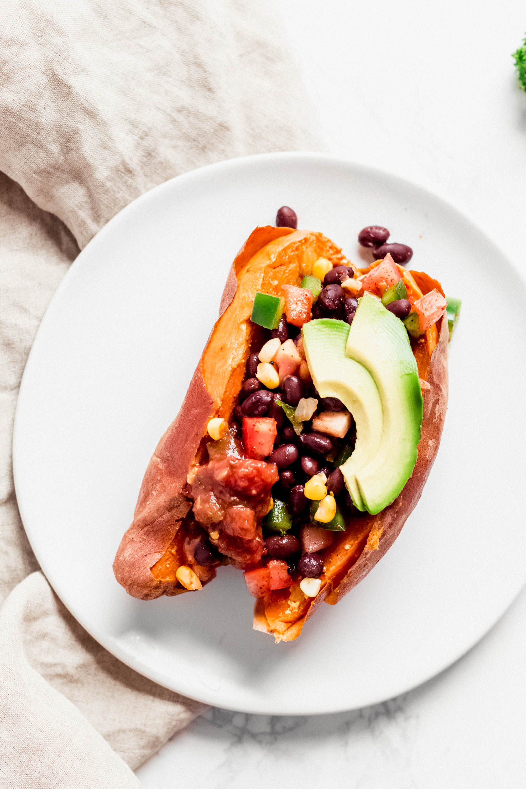a stuffed sweet potato filled with black beans, corn and diced tomatoes