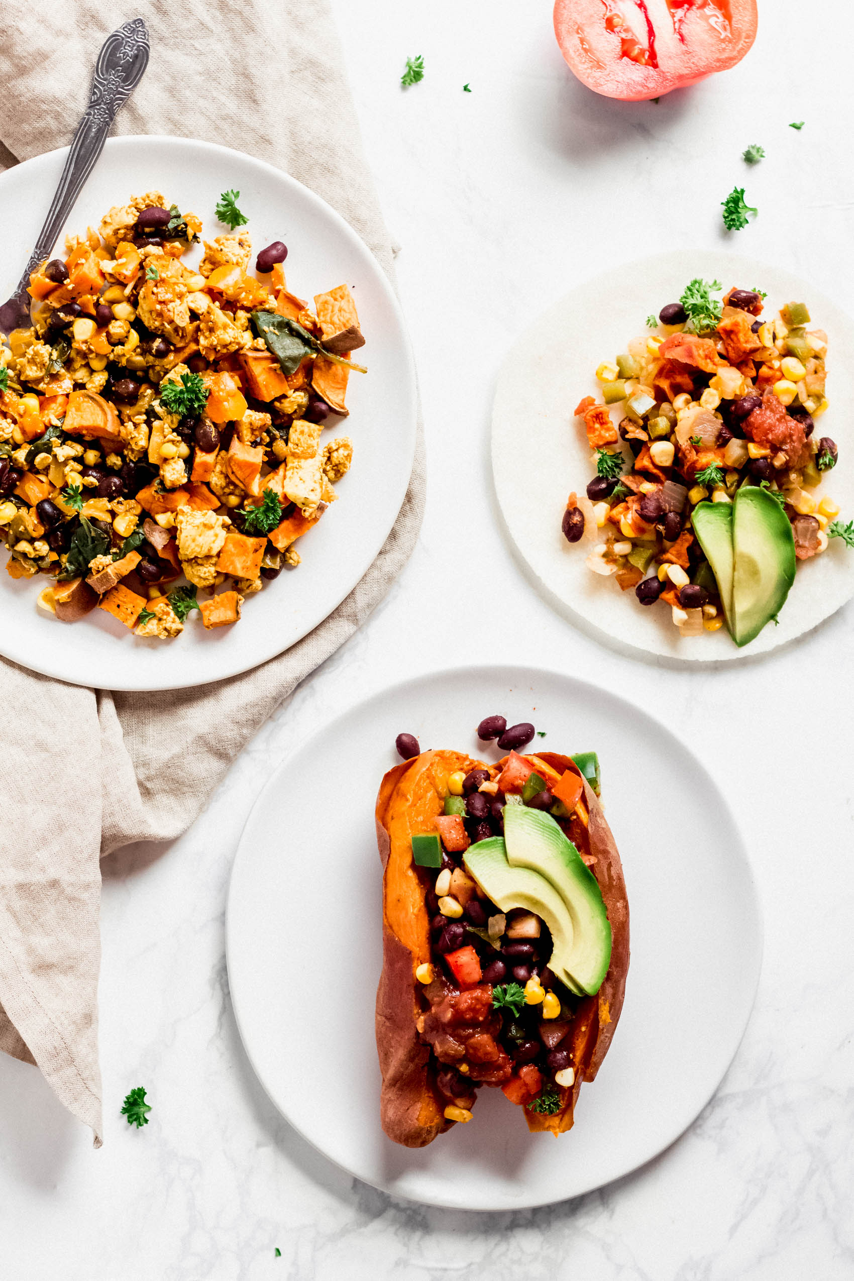 a plate of tofu scramble, a stuffed sweet potato and a sweet potato and black bean taco