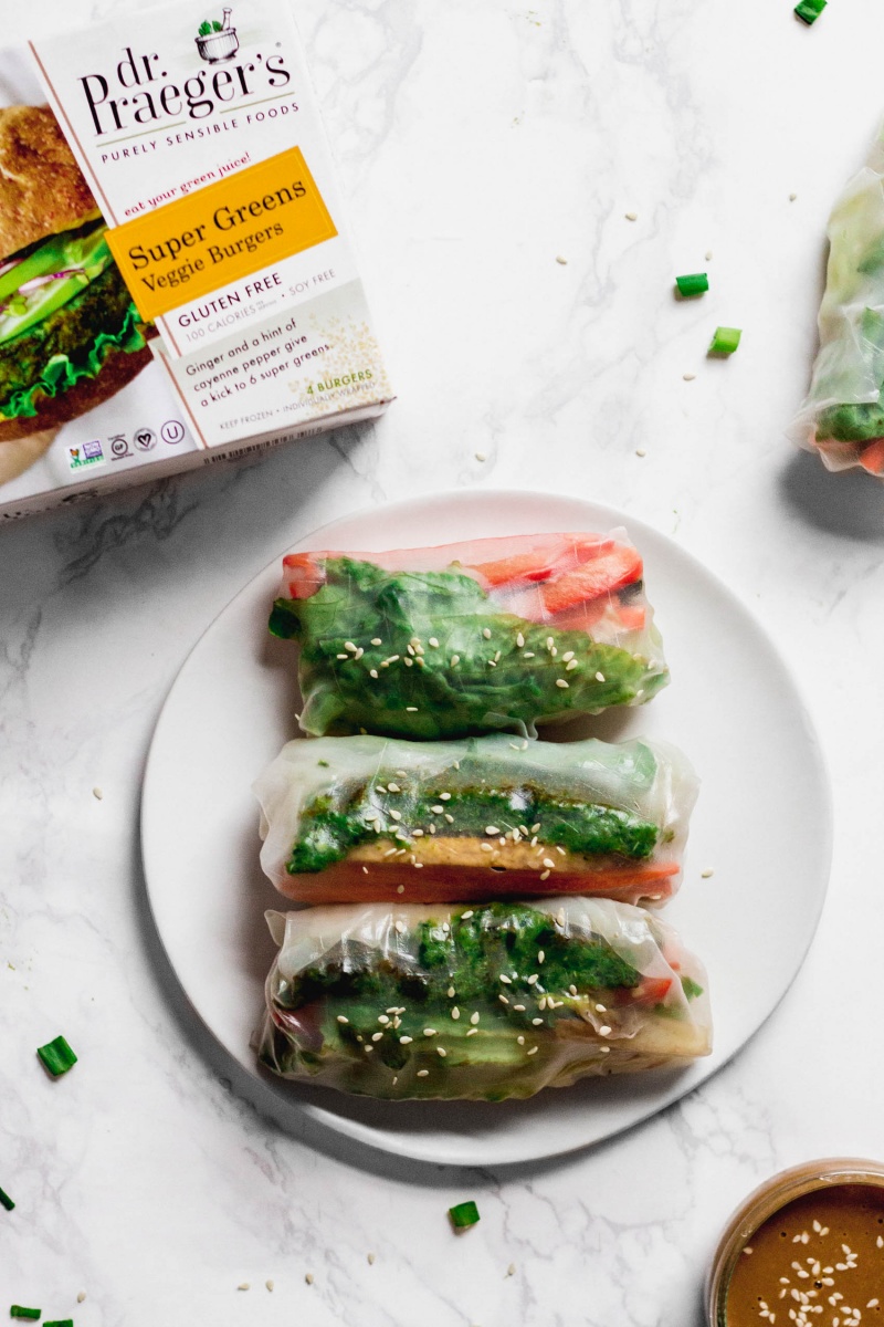 a plate of three vegan spring rolls next to a box of Dr. Praeger's Super Greens Veggie Burgers