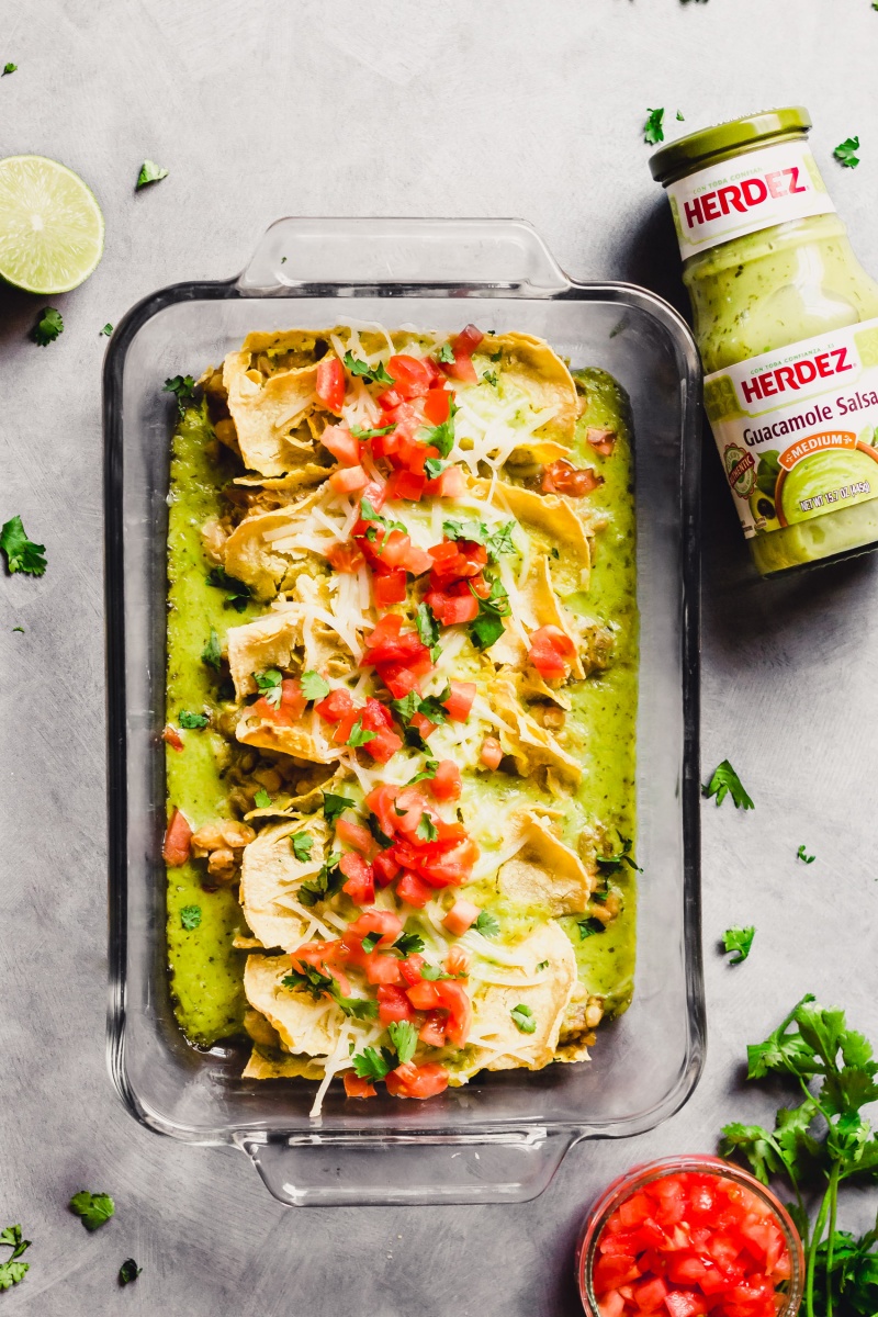 A tray of vegan enchiladas alongside a jar of guacamole salsa