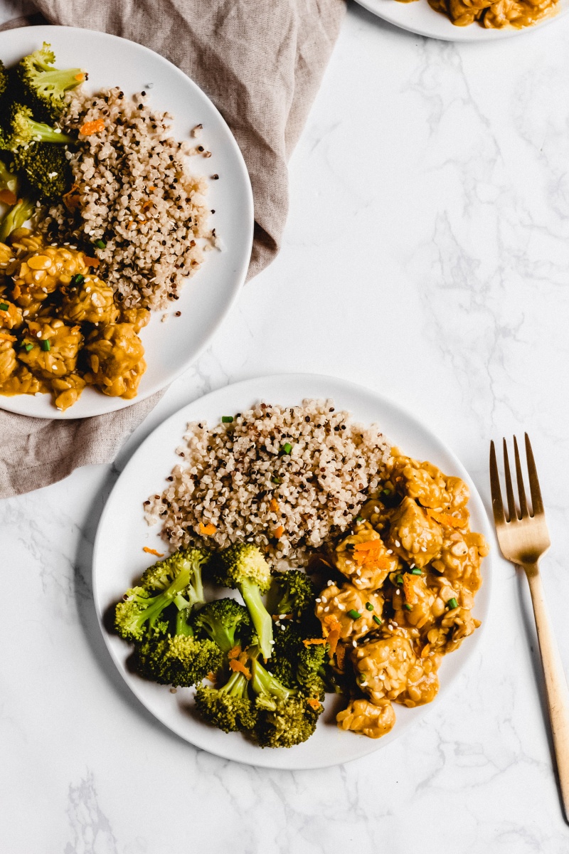 A plate of vegan orange tempeh served with broccoli and quinoa