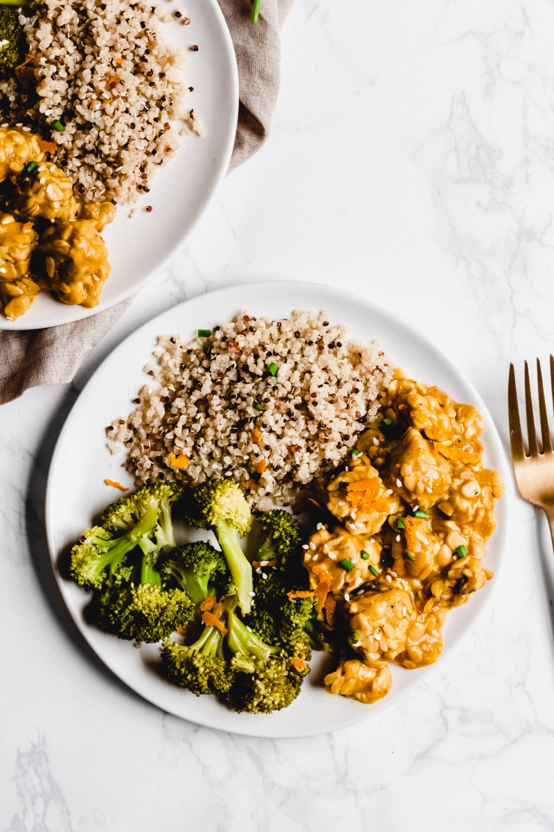 An overhead shot of a plate of broccoli, quinoa and orange tempeh