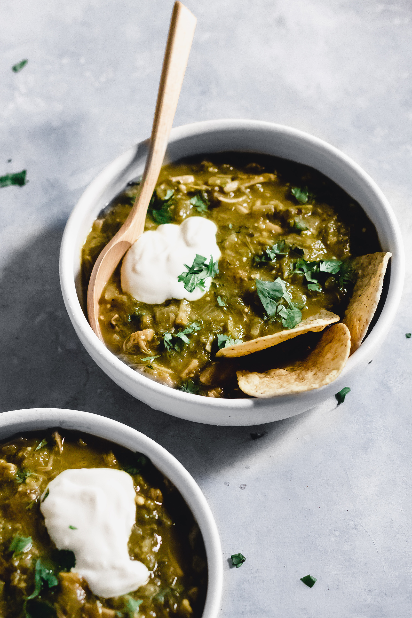 two bowls of vegan chili verde served with tortilla chips and vegan sour cream