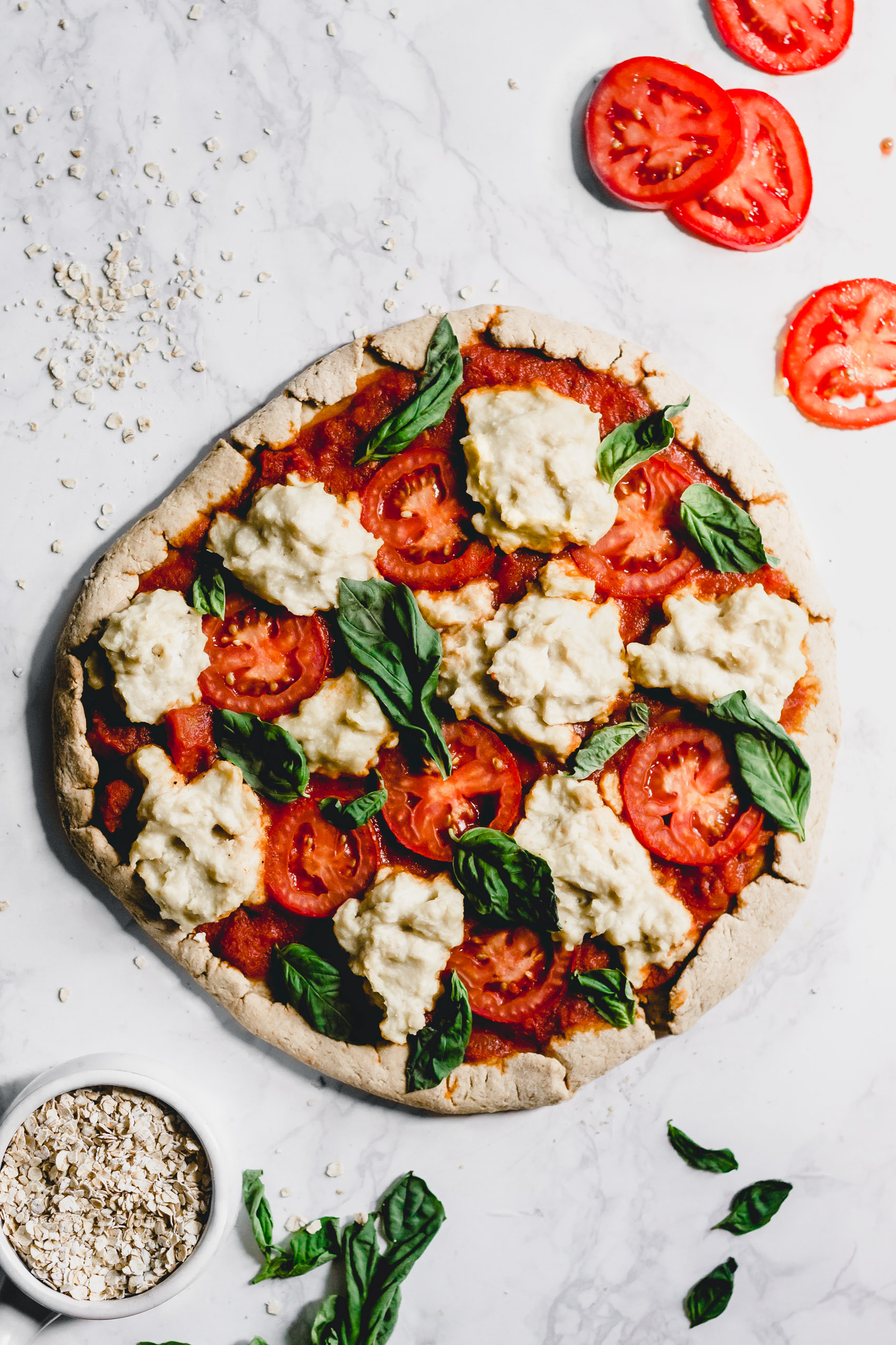 a margherita pizza surrounded by oats and tomatoes