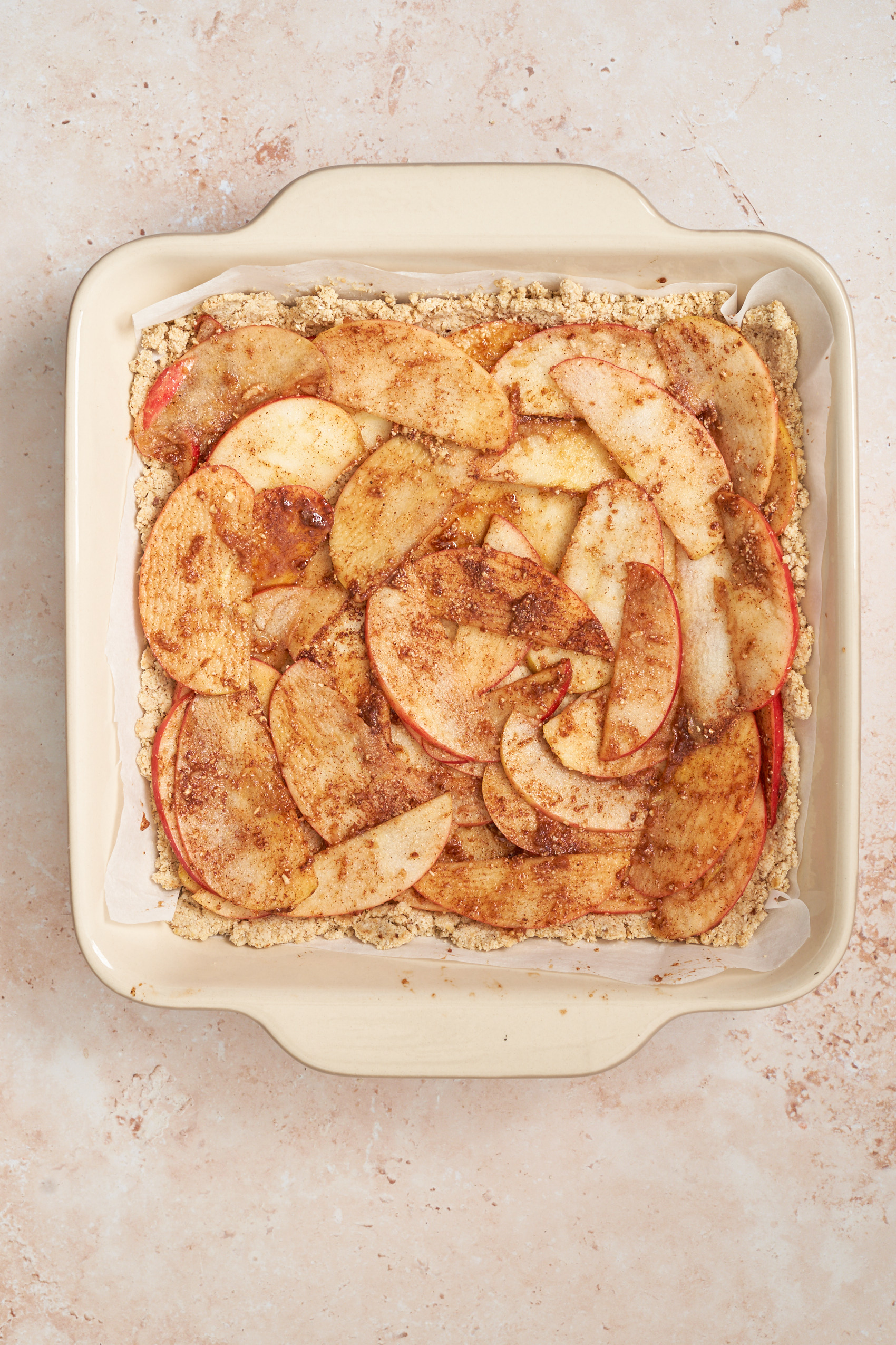 a baking dish with sliced apples on top of a vegan pie dough