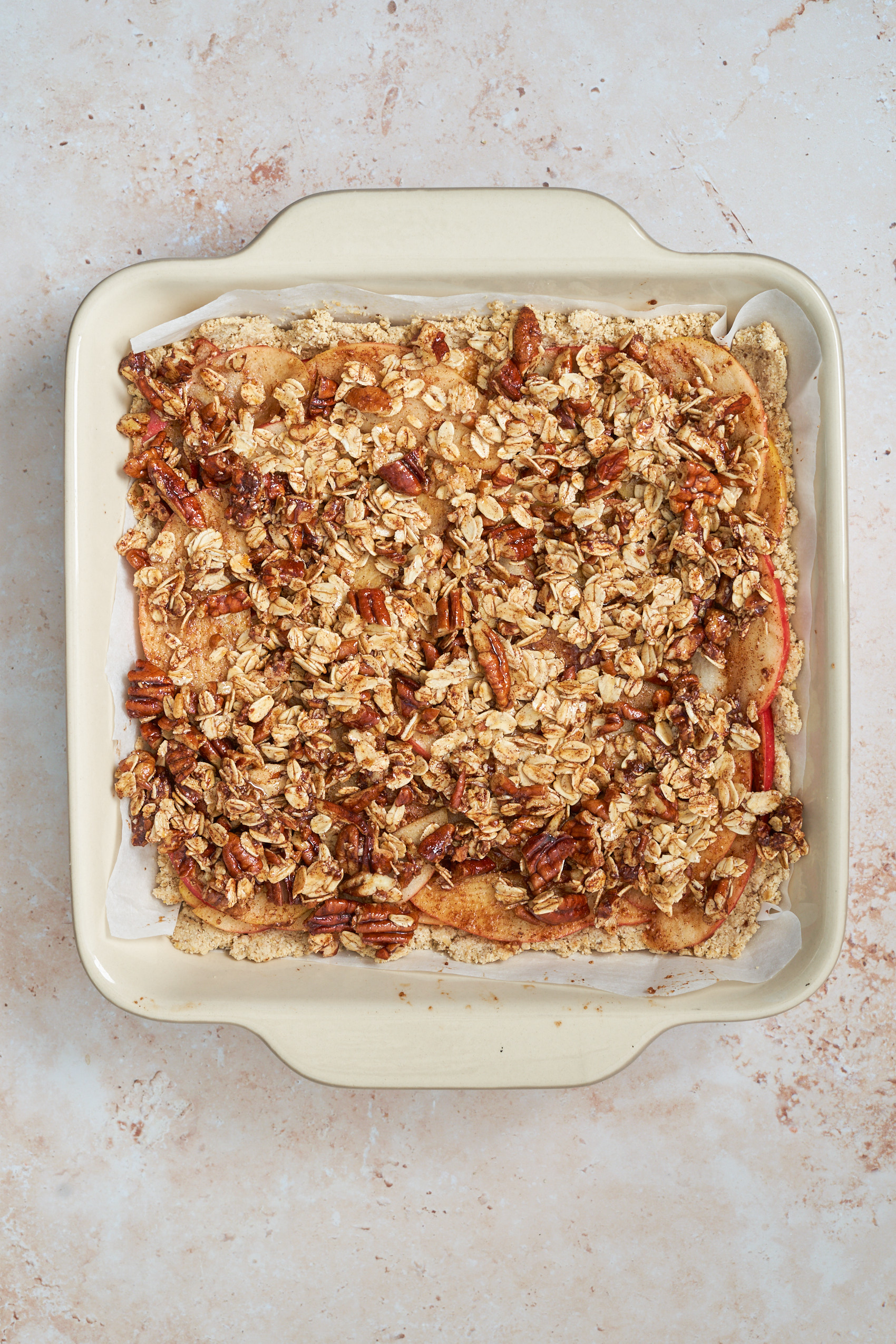 a gluten free crumble topping over sliced apples and pie dough in a baking dish
