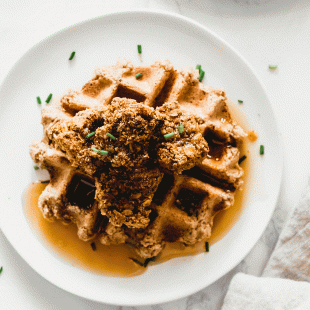 a plate of vegan chicken and waffles sprinkled with chopped chives