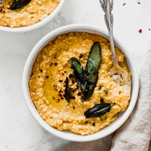 two bowls of pumpkin risotto topped with fried sage