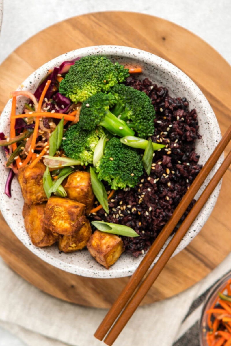 wooden board with a bowl of vegetables and chopsticks