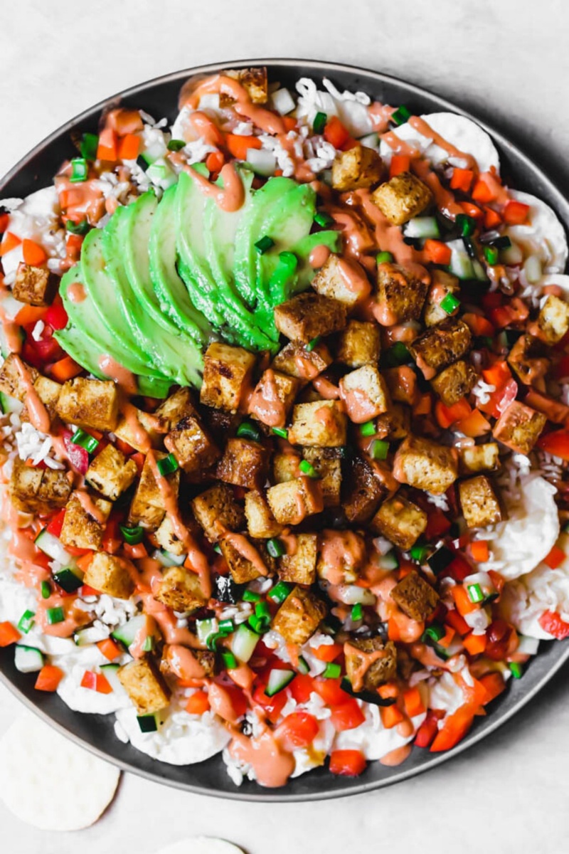 black plate of nachos with sushi toppings