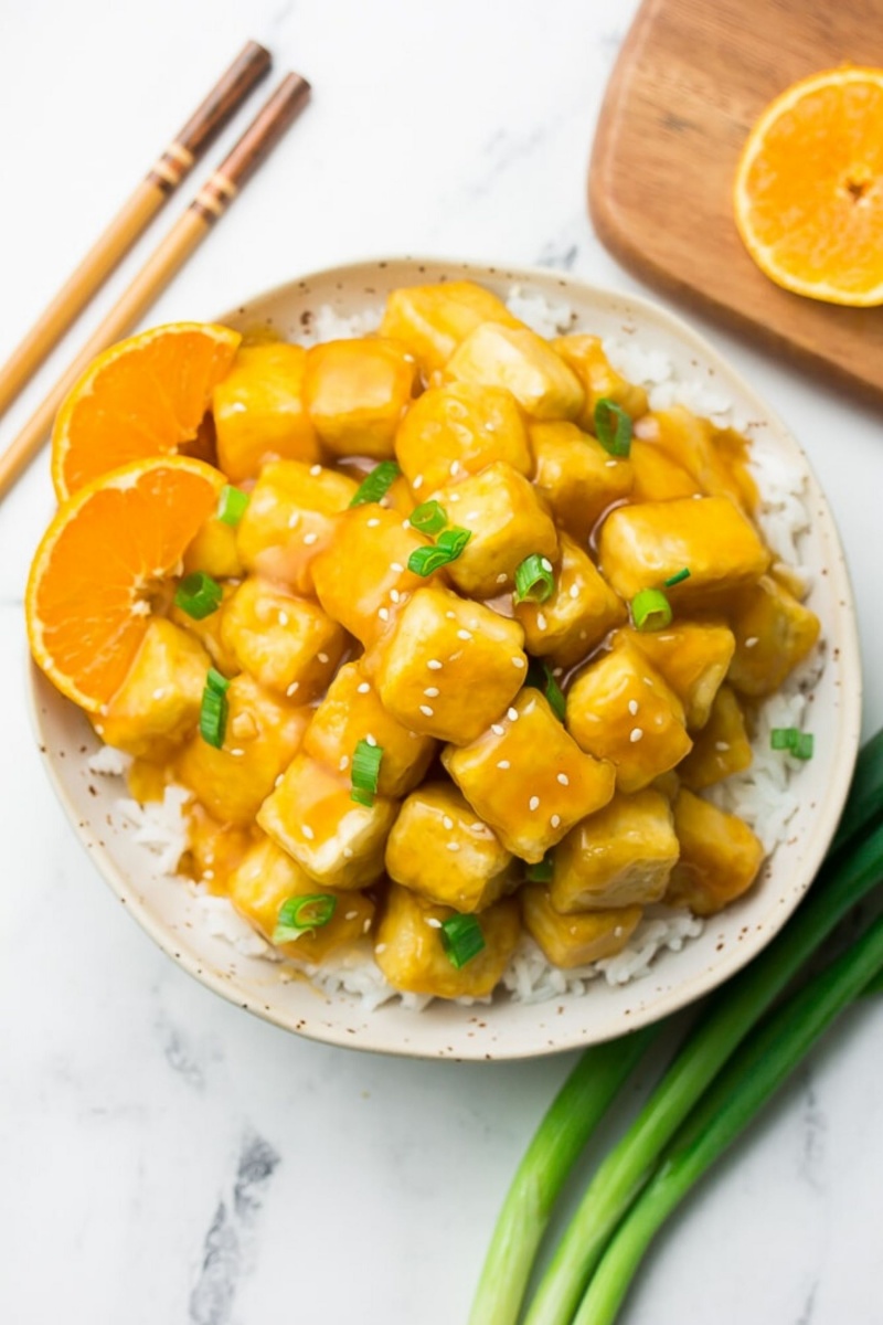 orange tofu on a bed of white rice with orange slices