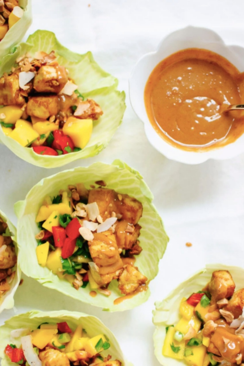 multiple green cabbage wraps with vegetables and tofu with peanut sauce 