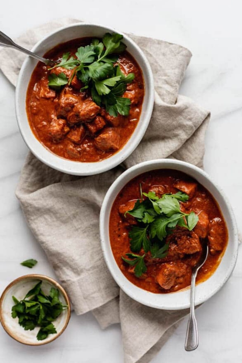 two bowls with red tikka masala topped with cilantro 