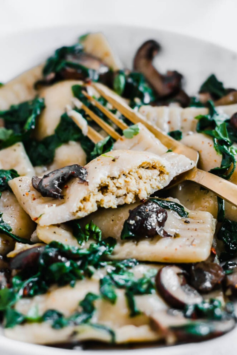 gold fork with a plate of ravioli and mushrooms 